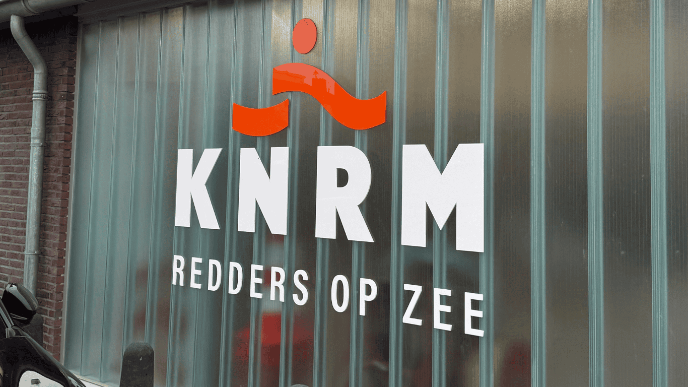 Het logo en slogan van de KNRM